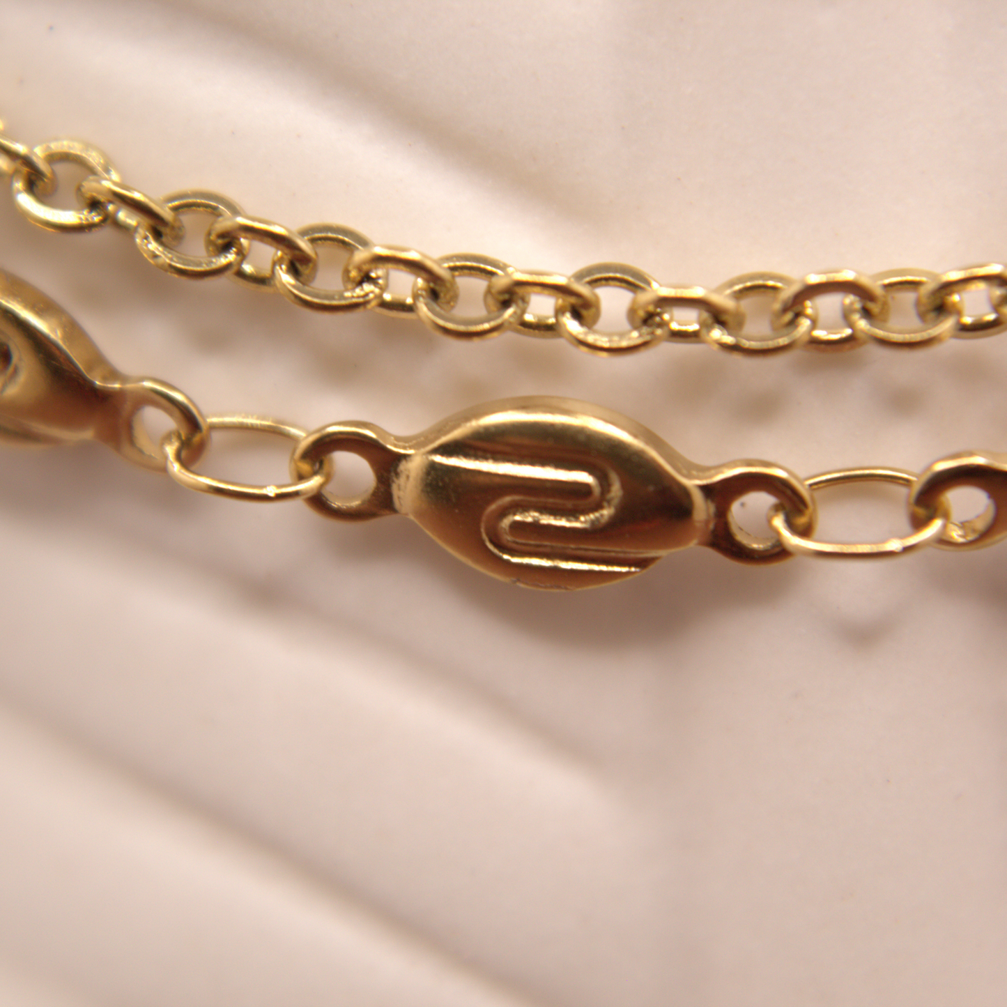 Gold chain with intricate links on a beige fabric background