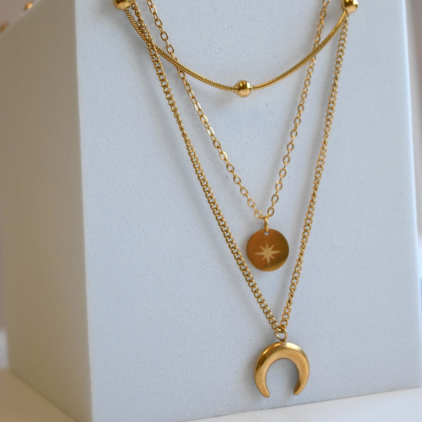Gold necklaces with pendants on a white stand