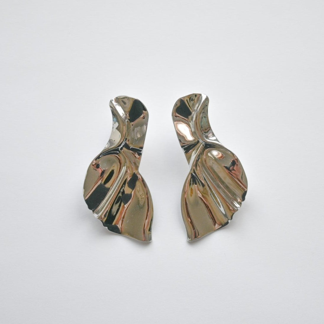 Rhodium-plated silver earrings with an abstract design resembling a mermaid's tail, displayed against a white background.
