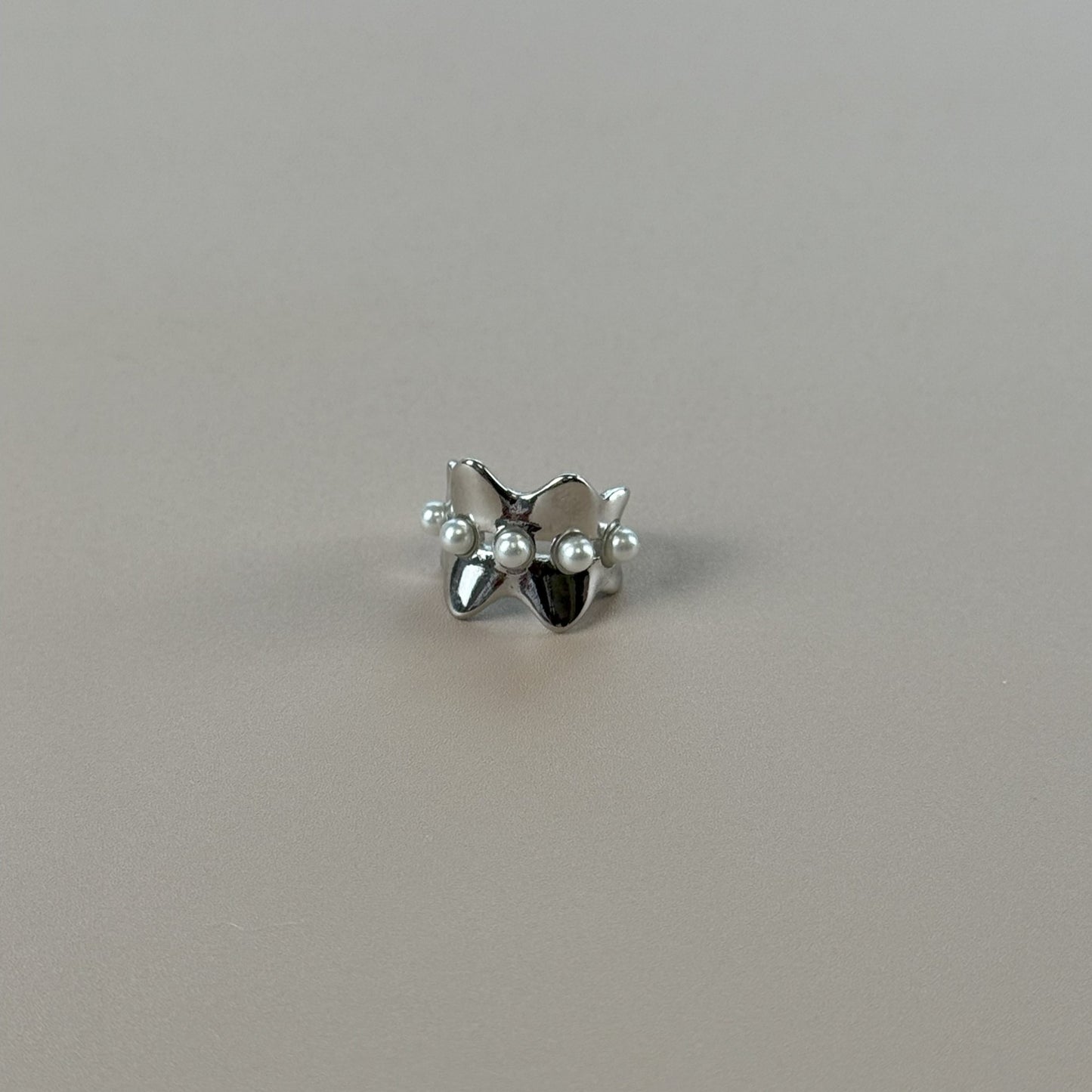Silver earcuff with pearls on a gray background