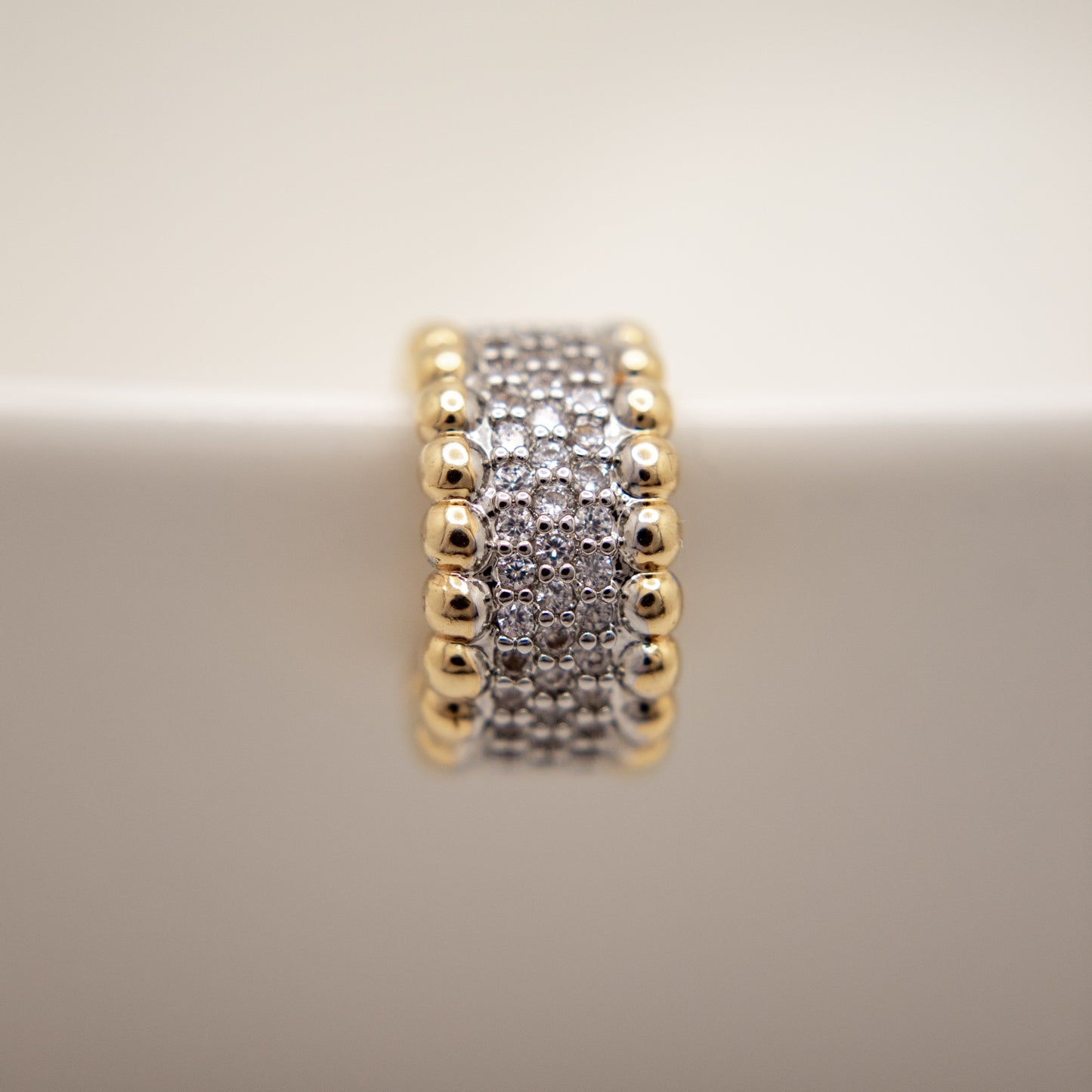 Gold and silver beaded ring on a beige background