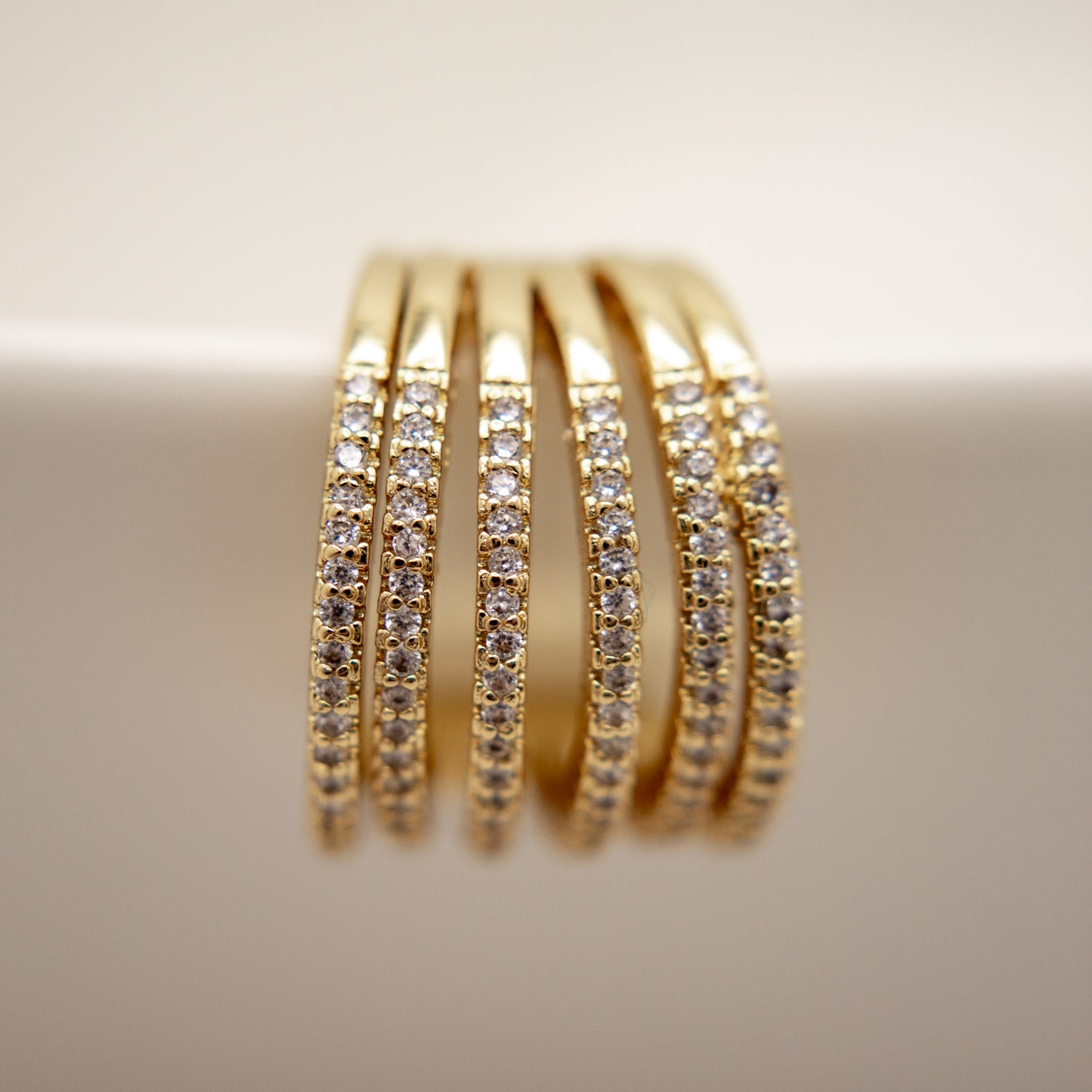 Gold ear cuff with embedded diamonds on a neutral background