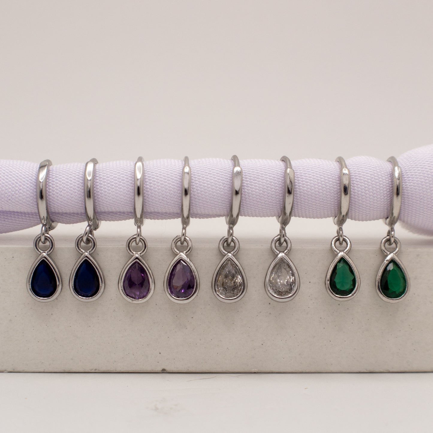 Set of teardrop-shaped jewelry charms with different colored stones on a white background