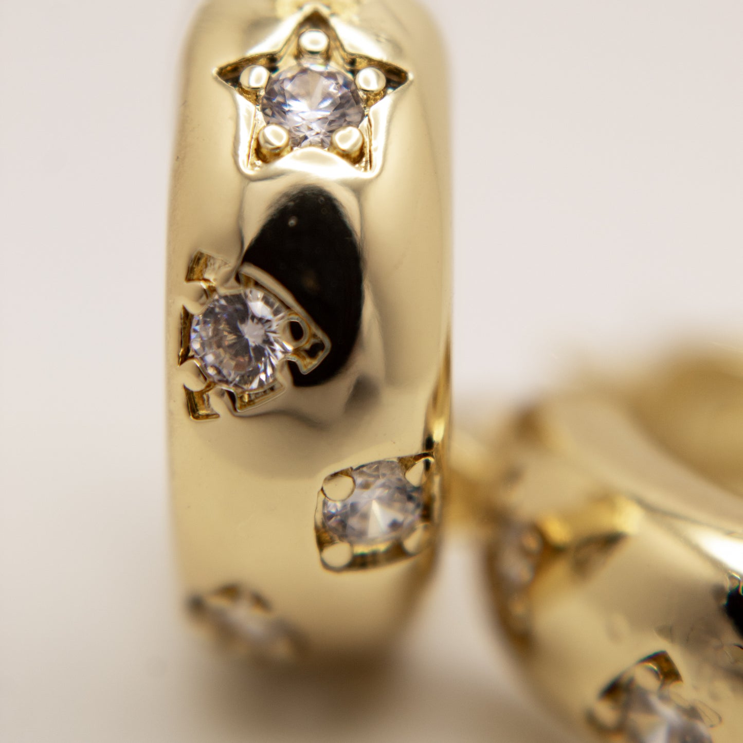 Gold earring with star and gemstone design on a light background
