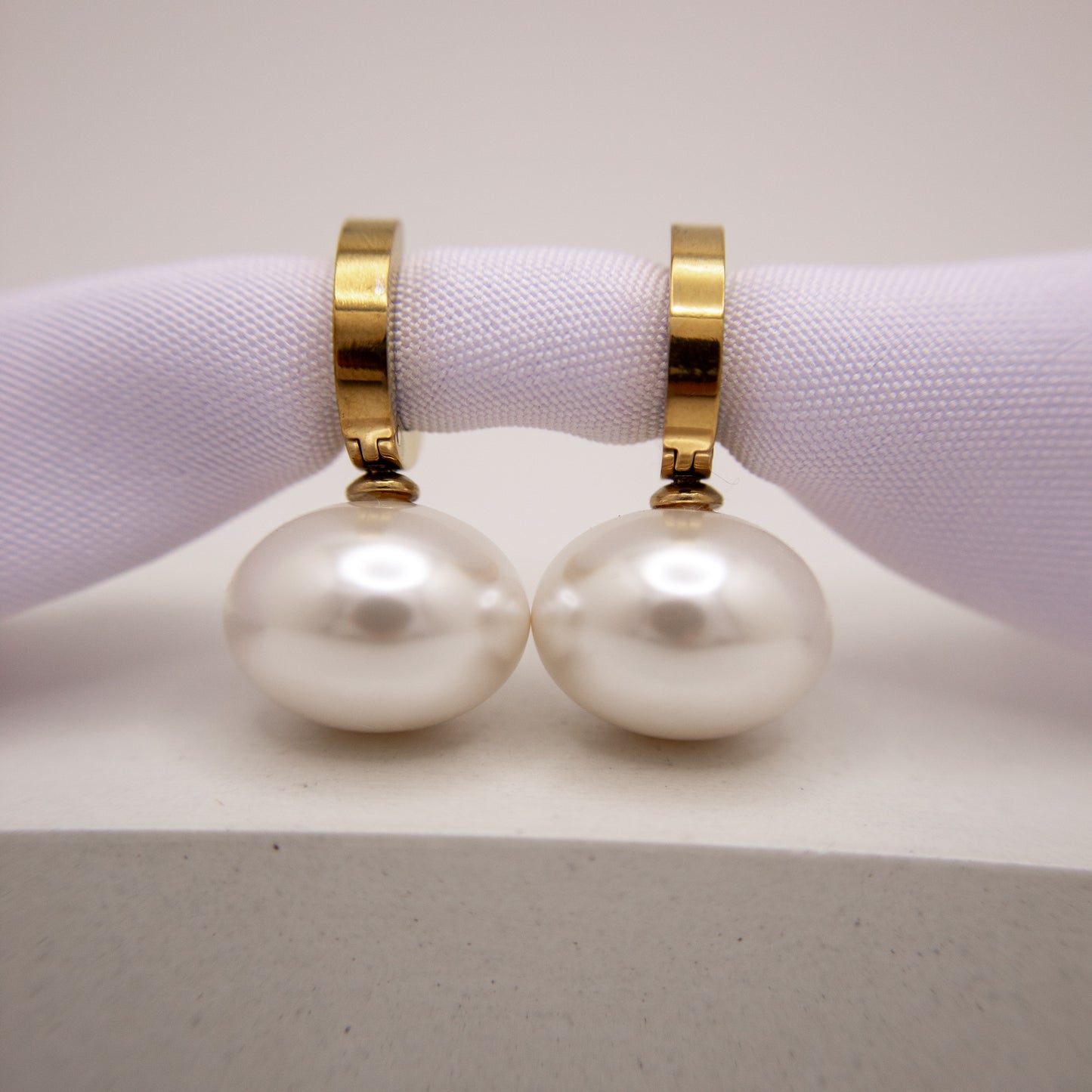 Pearl earrings with gold clasps on a white surface