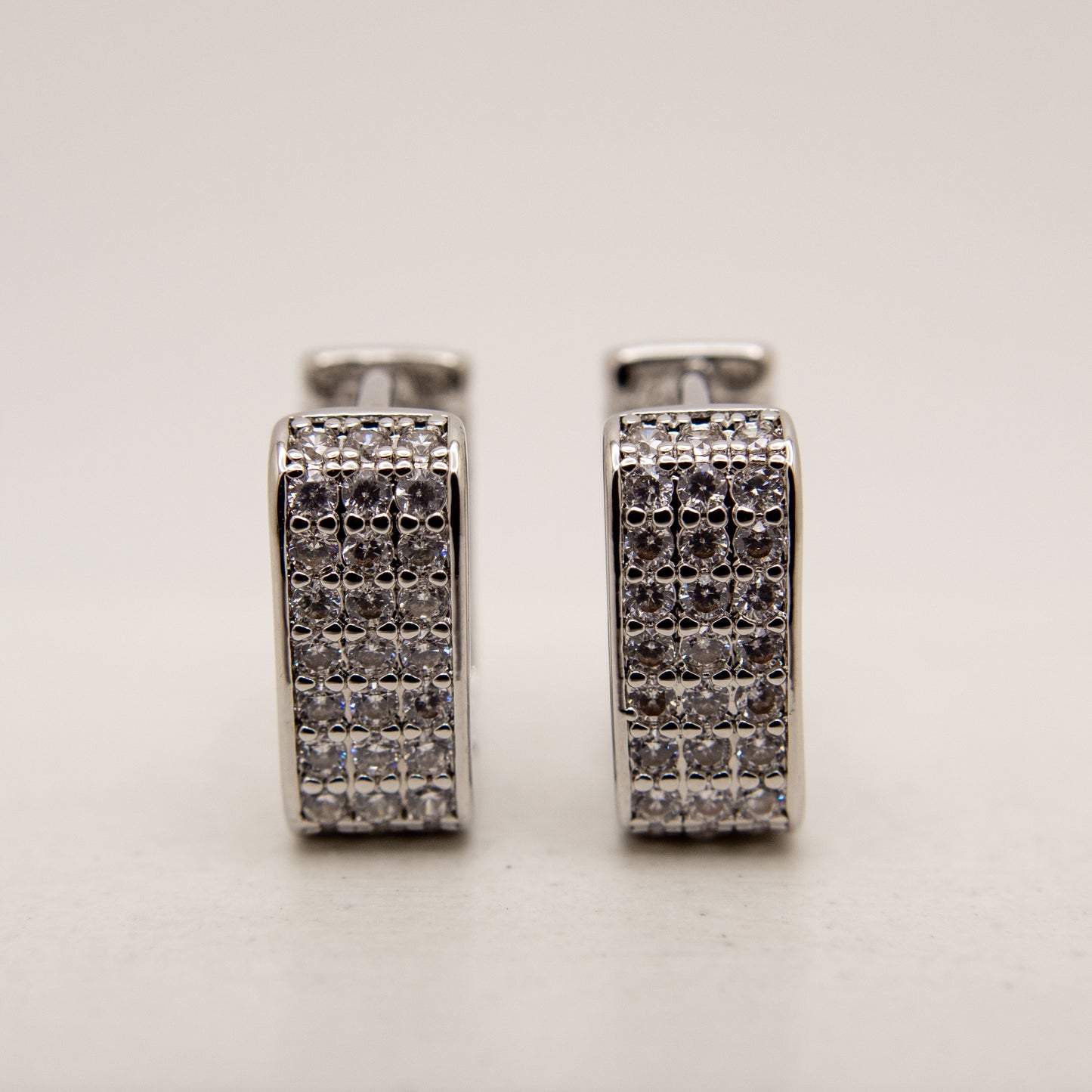 Pair of silver hoop earrings with embedded stones on a light gray background