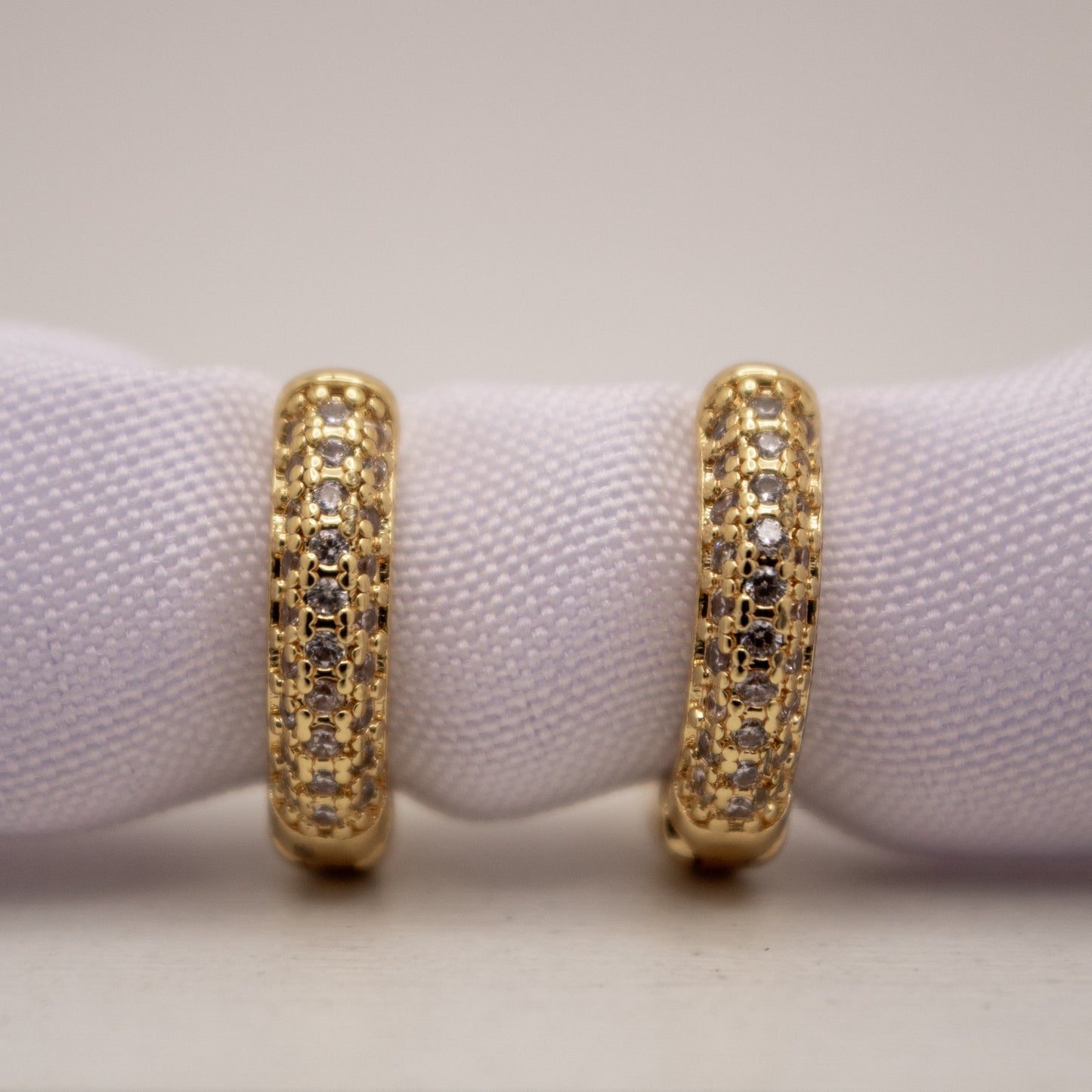 Gold hoop earrings with embedded stones on a white background