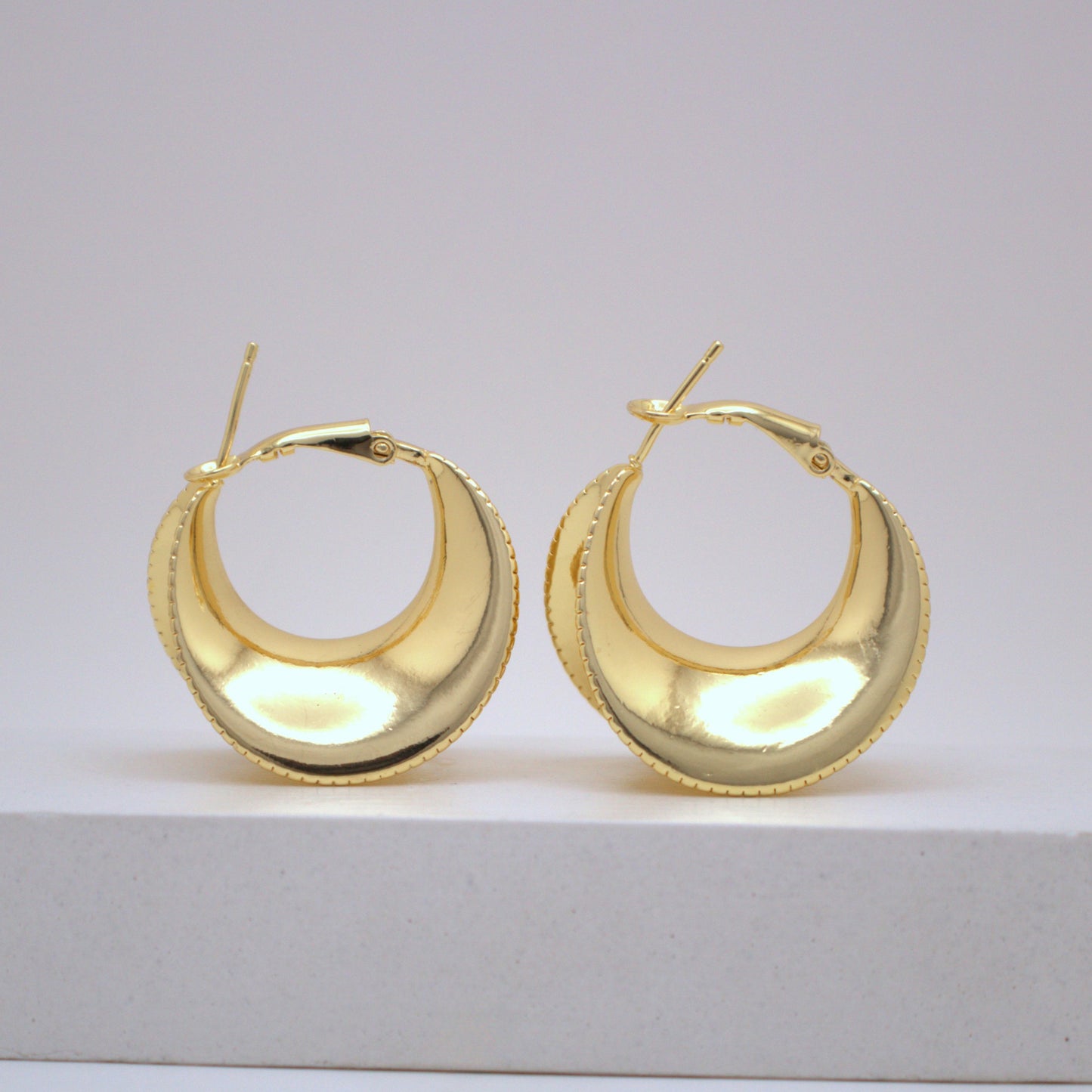 Pair of gold hoop earrings on a light gray background