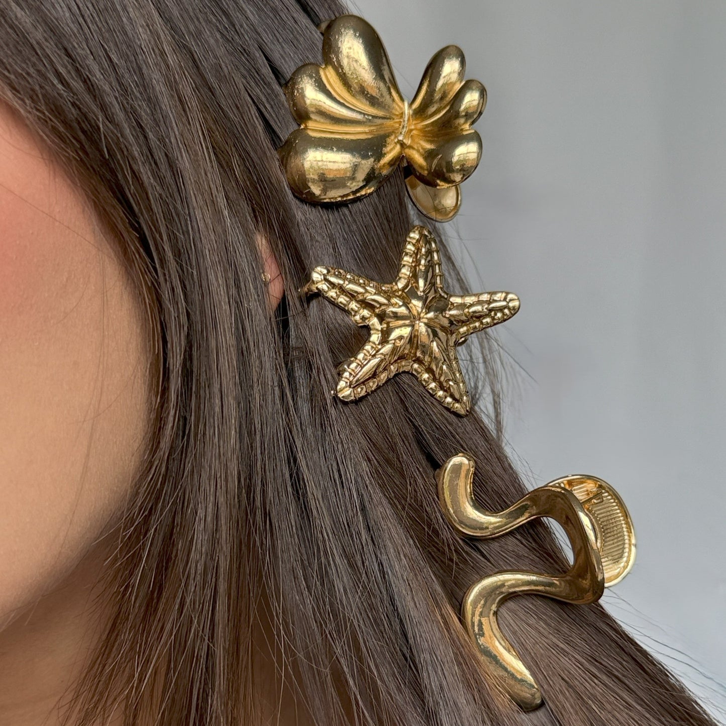 Gold hair accessories including a shell and starfish design on a person's hair.