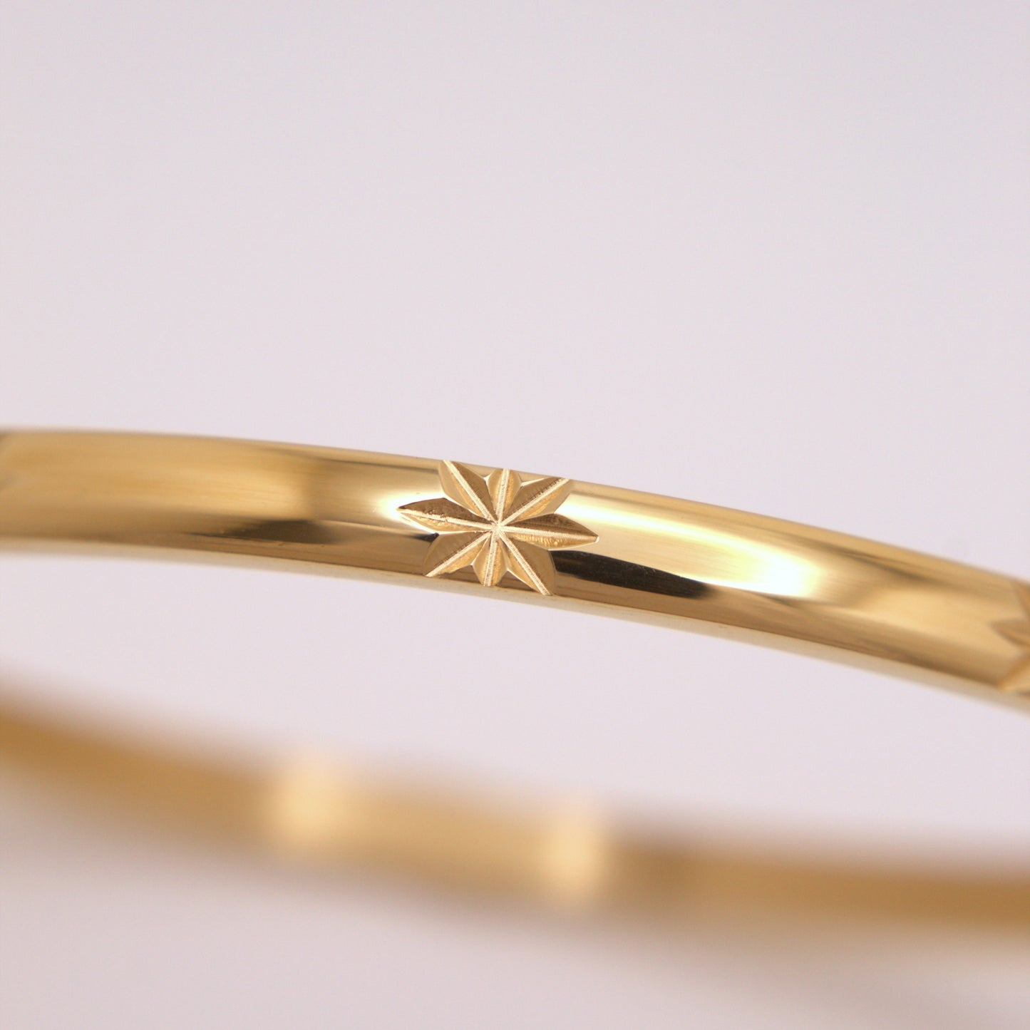 Gold bracelet with star design on a light gray background