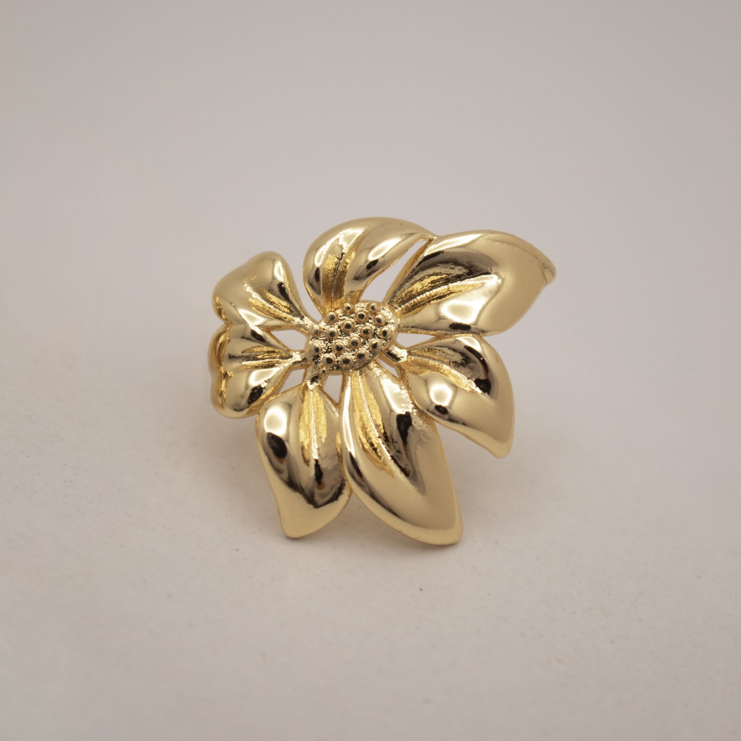 Gold flower-shaped brooch on a light gray background