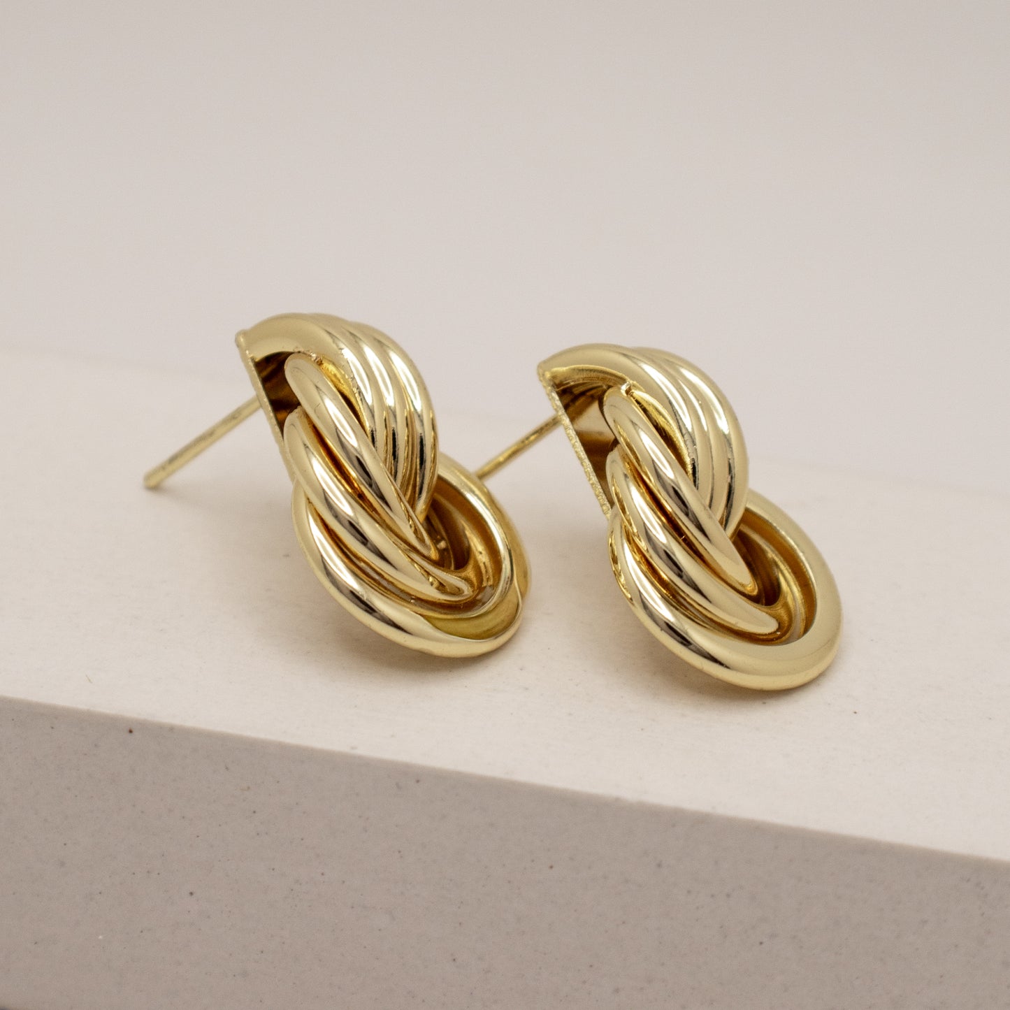 Pair of gold knot earrings on a light background