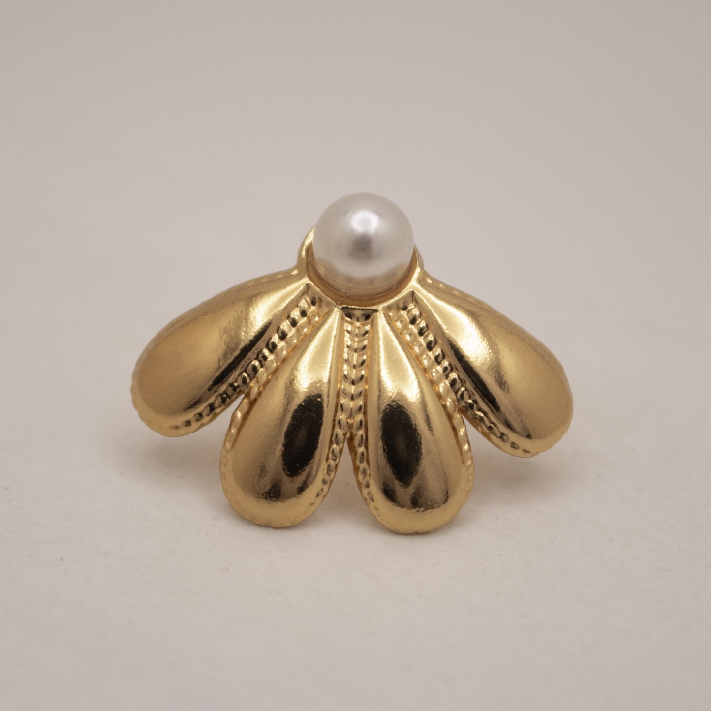 Gold earring with a pearl on a beige background