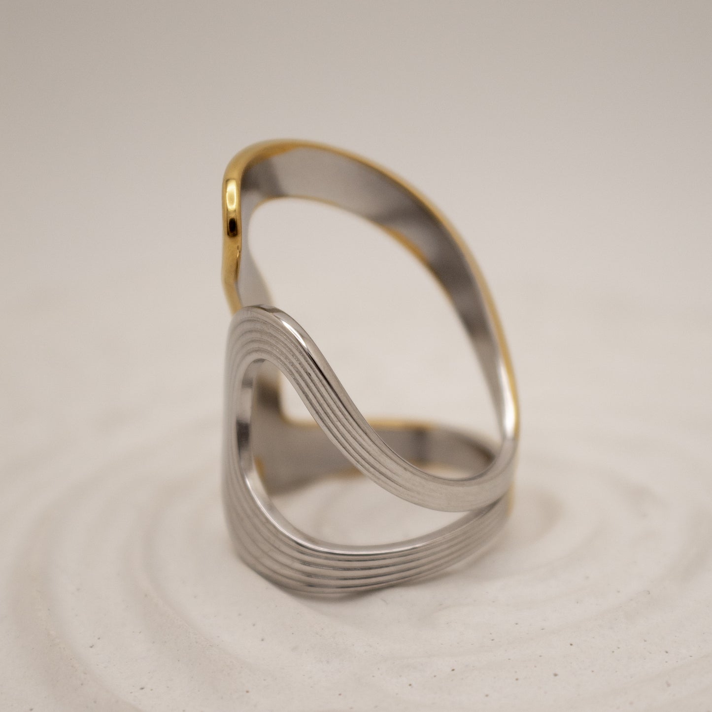 Silver ring with gold accent on a beige background