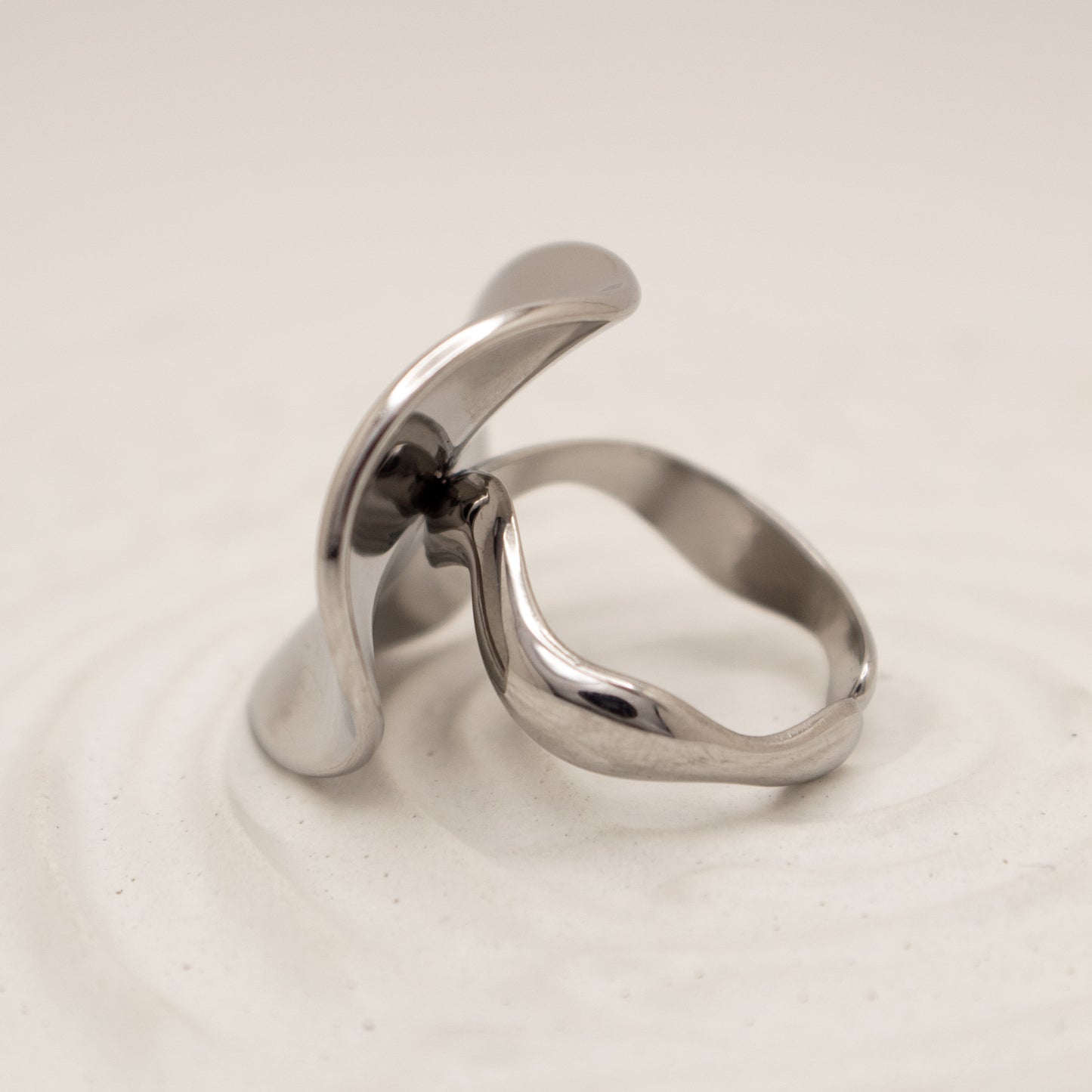 Silver ring with a modern design on a light beige background