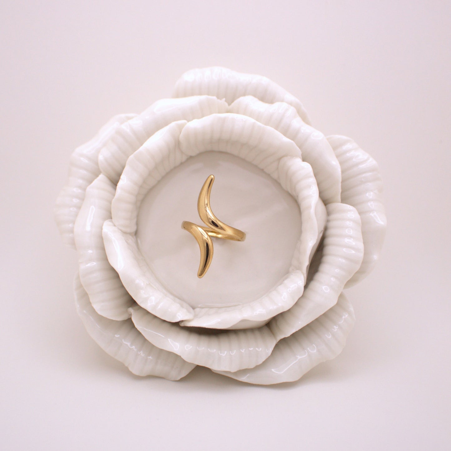 Gold ring on a white ceramic dish shaped like a flower