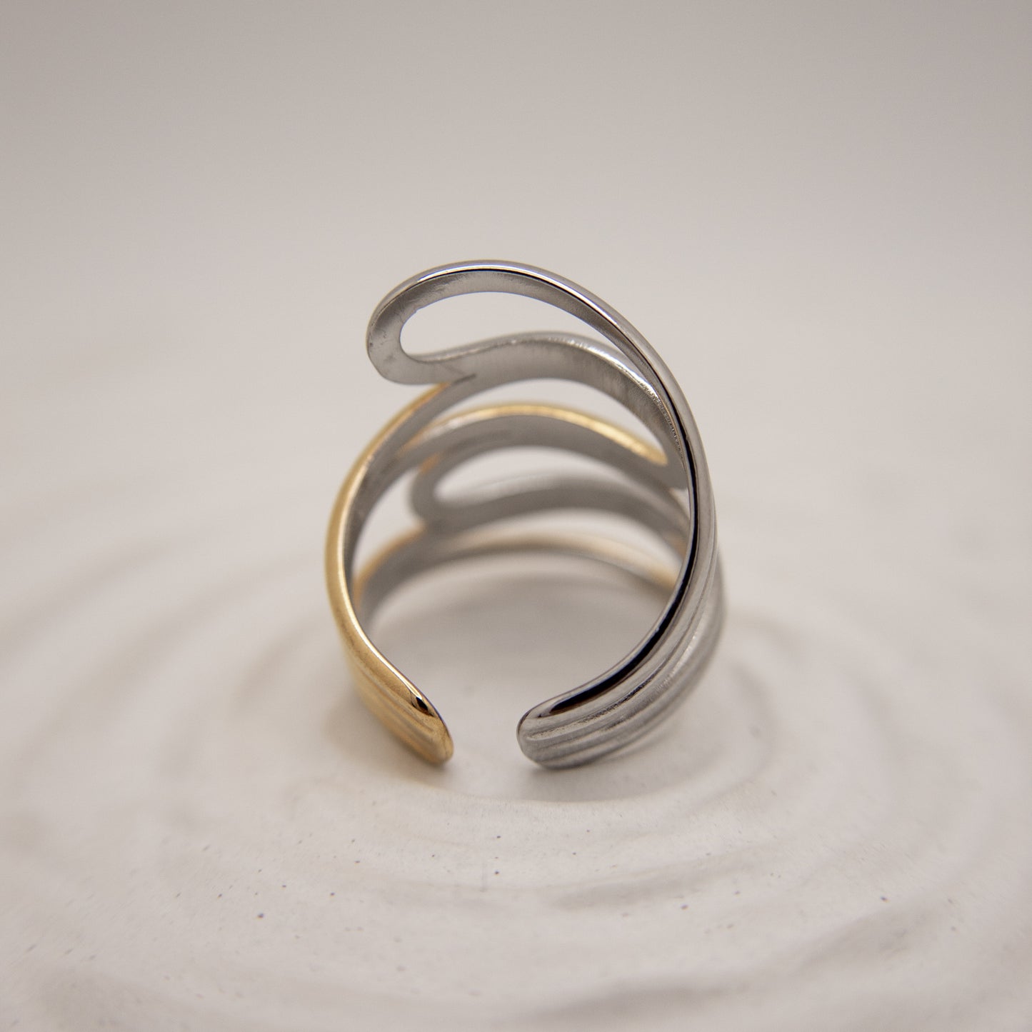 Silver and gold ring on a light gray background