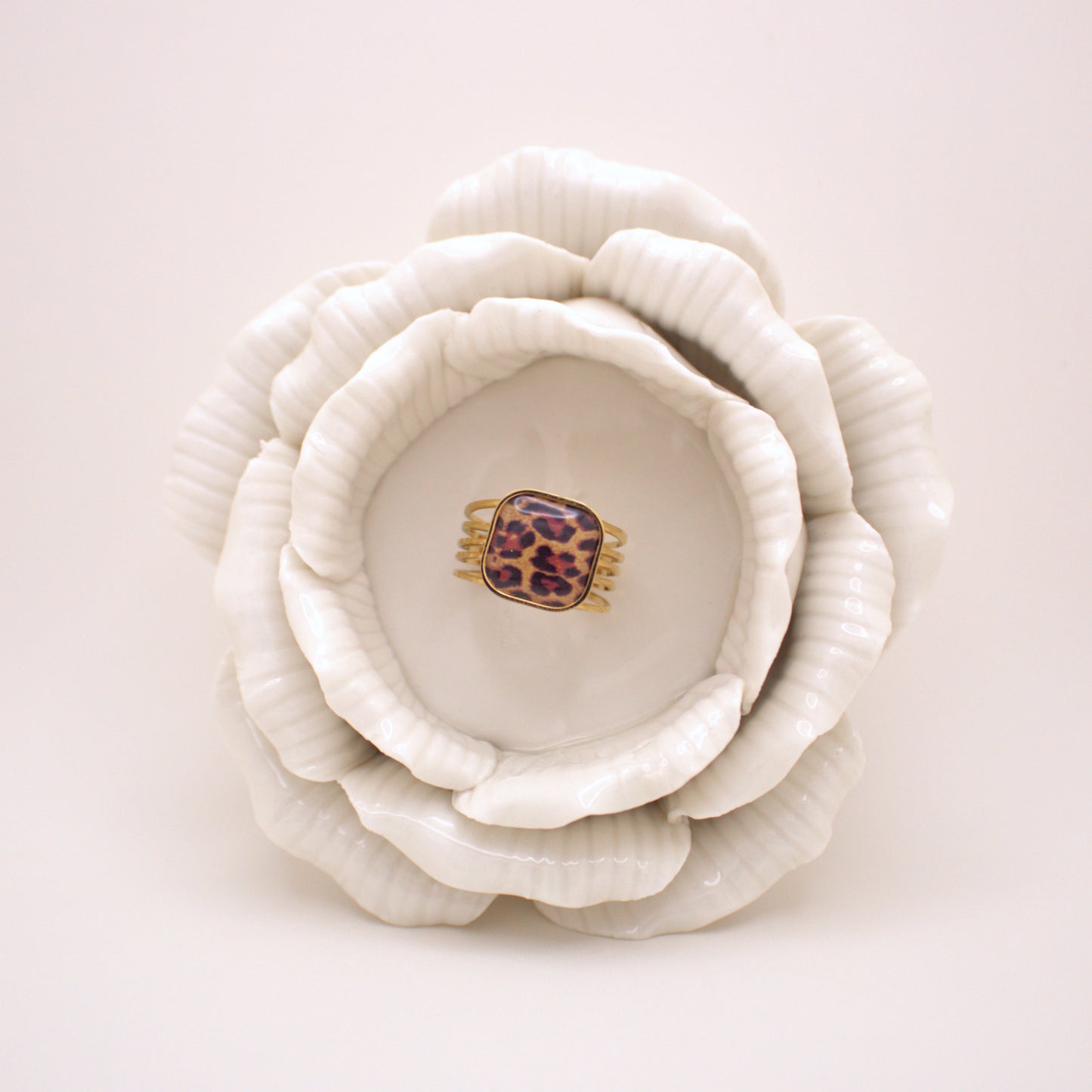 White ceramic flower with a leopard print hair clip inside on a white background