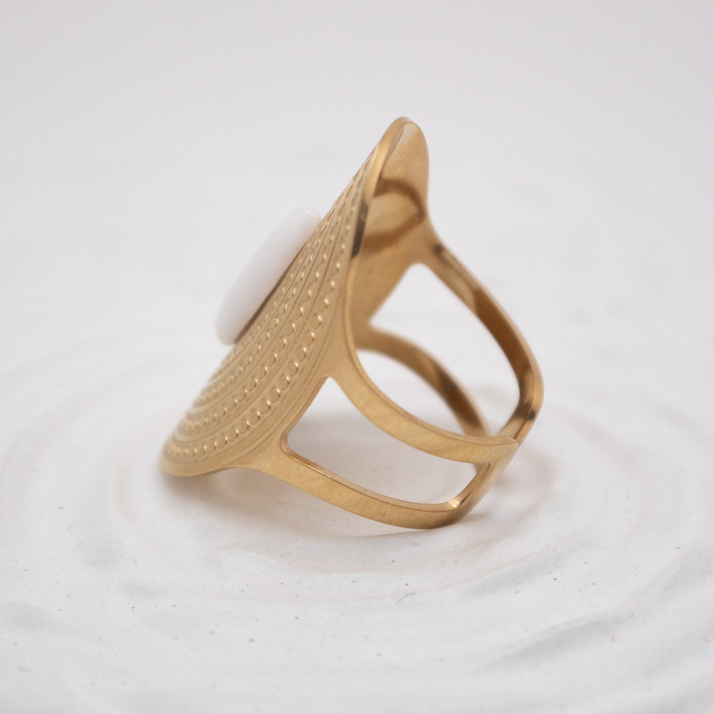 Gold ring with a textured design on a white background