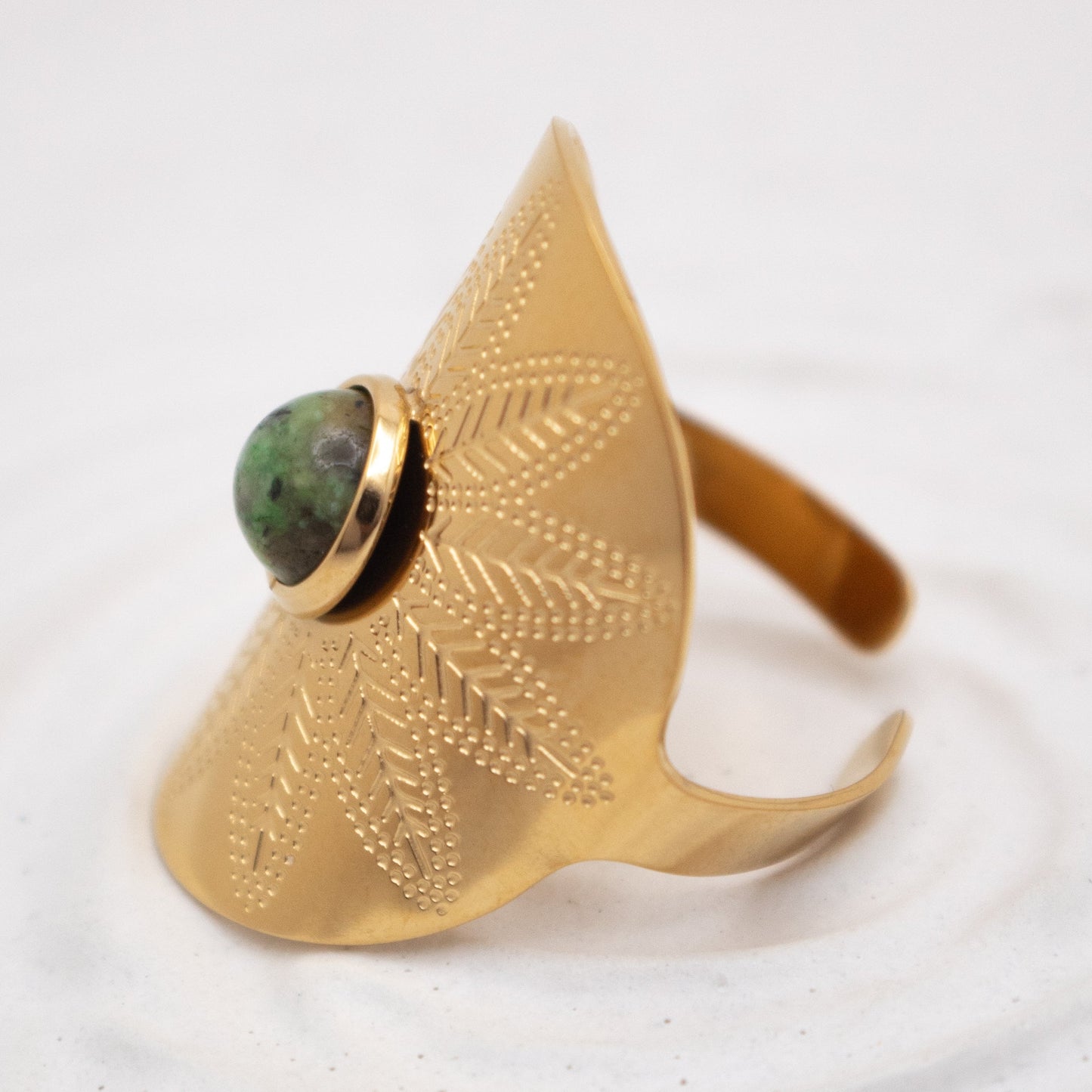 Gold ring with green gemstone on a white background