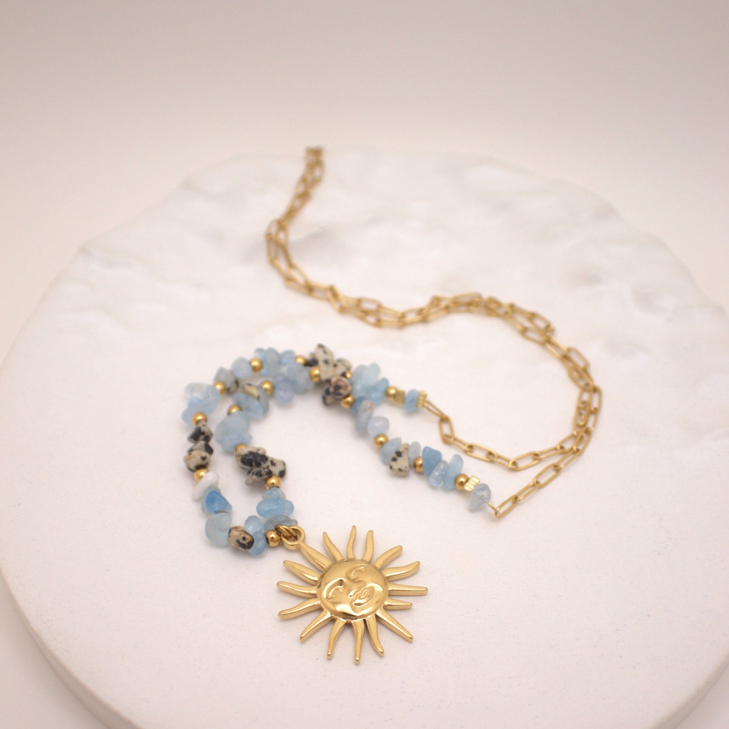 Necklace with sun pendant and beaded chain on a white surface
