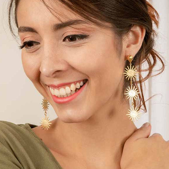 Woman wearing gold star-shaped earrings with a plain background