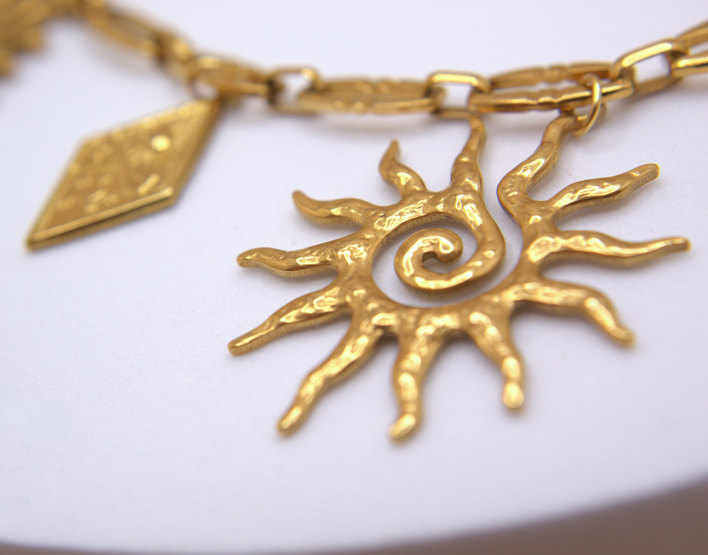 Bold gold charm necklace, sun-inspired multi-pendant design in stainless steel.