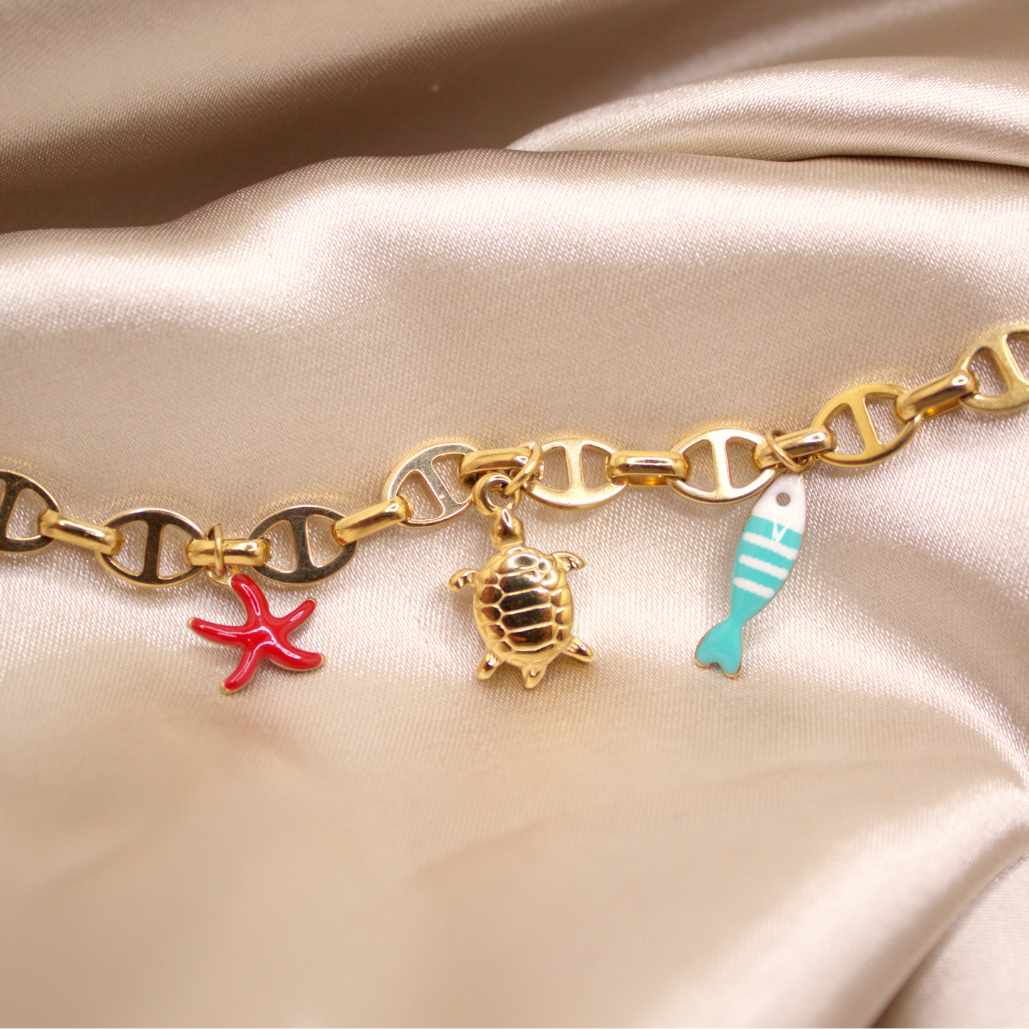 Ocean Voyage Bracelet in gold with turtle, red starfish, and blue fish charms