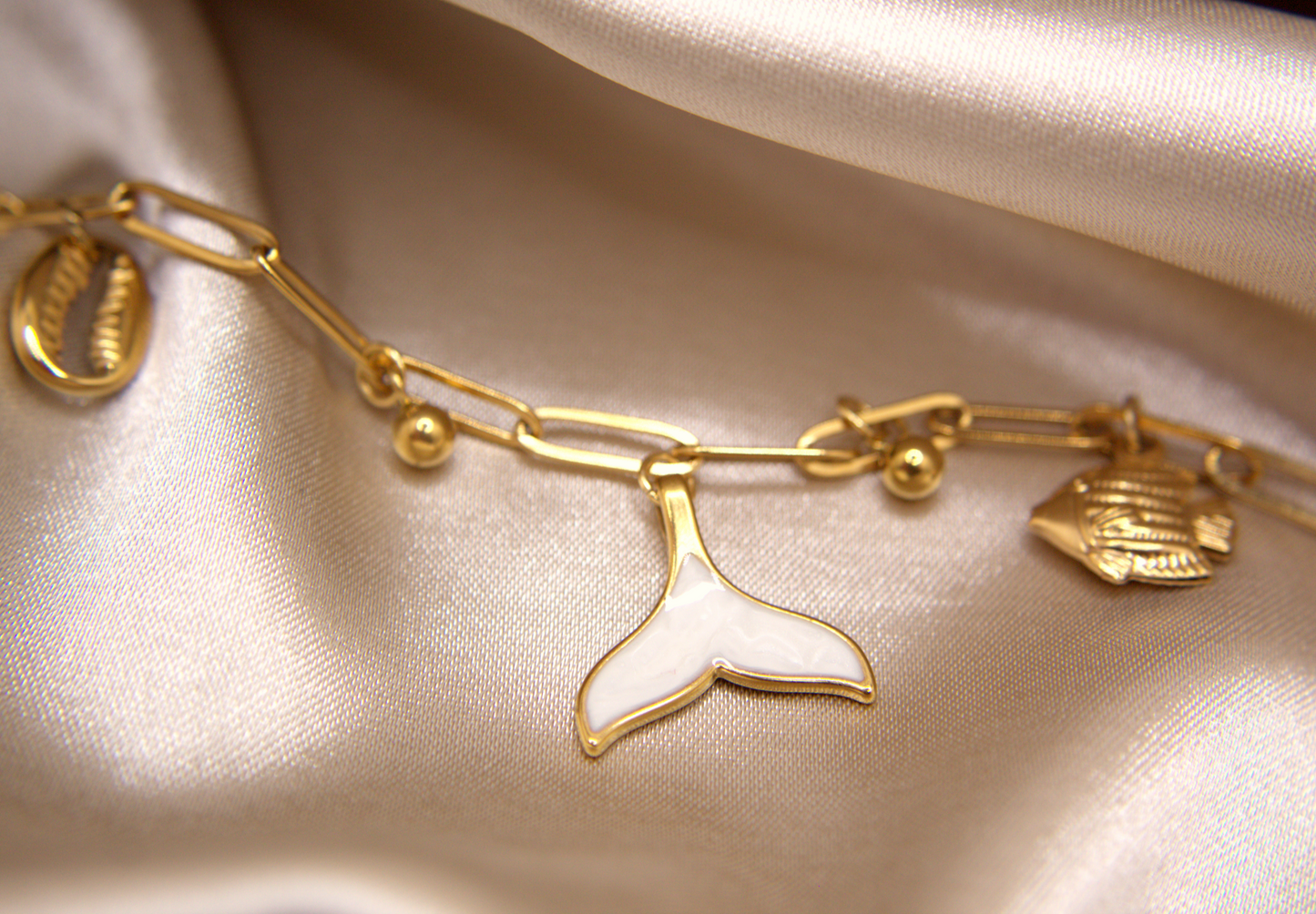 Siren’s Whisper Bracelet in gold with white enamel mermaid tail, fish, and shell charms