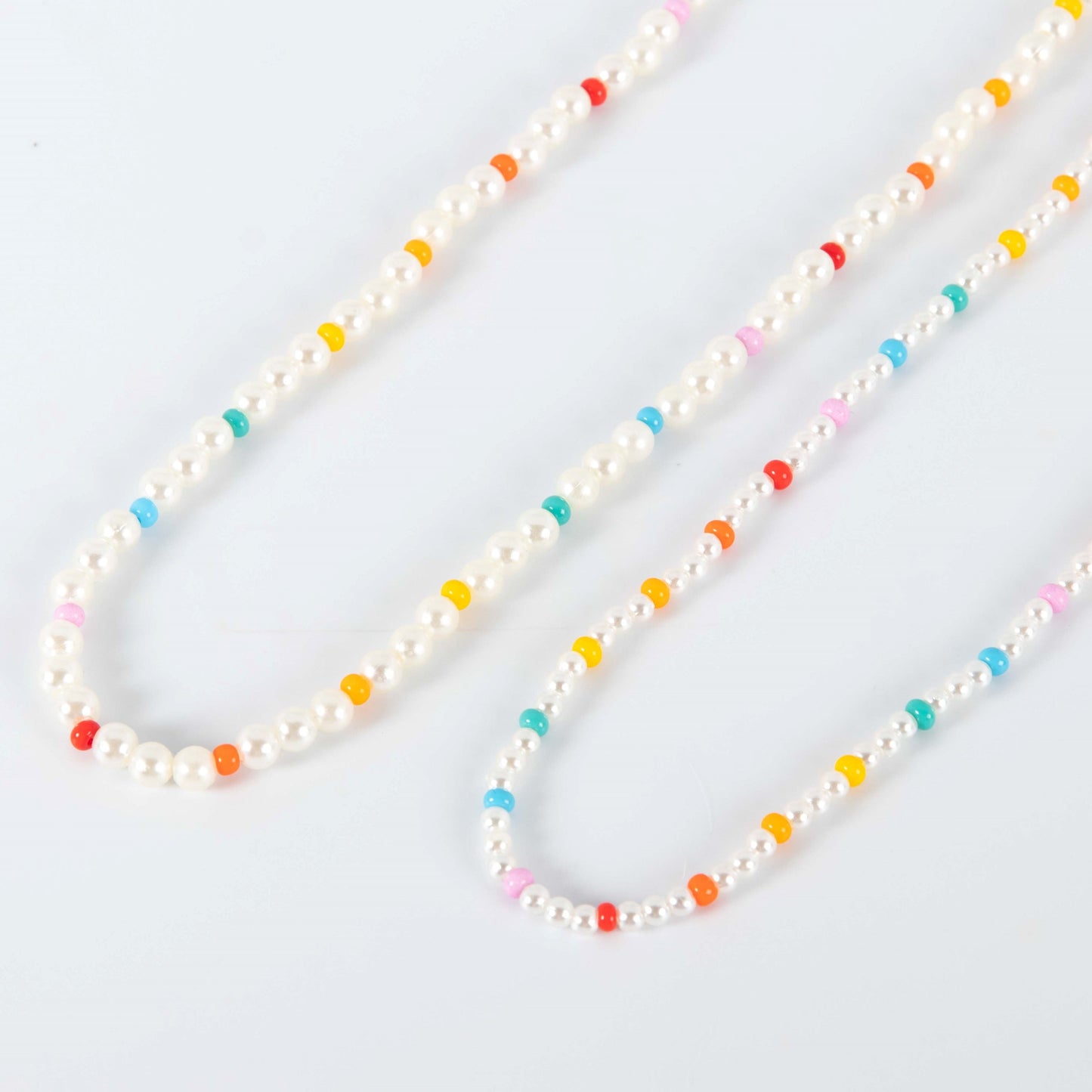 Necklace with white pearls and multicolored beads on a light gray background