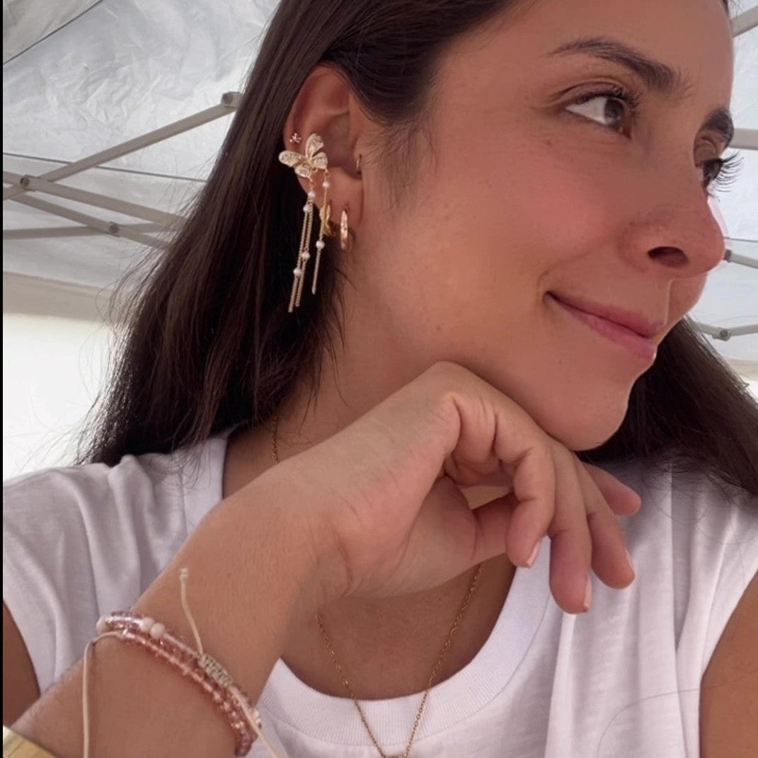 Woman wearing earrings and a necklace, with a white background