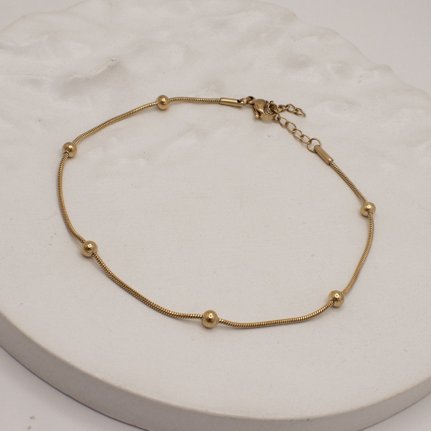 Gold bracelet on a white marble surface