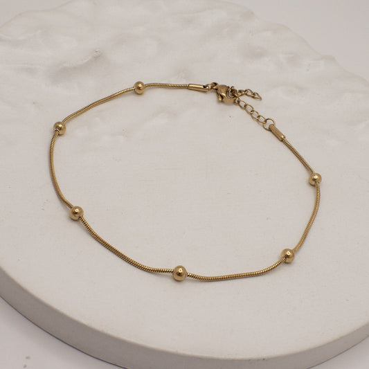 Gold bracelet on a white marble surface
