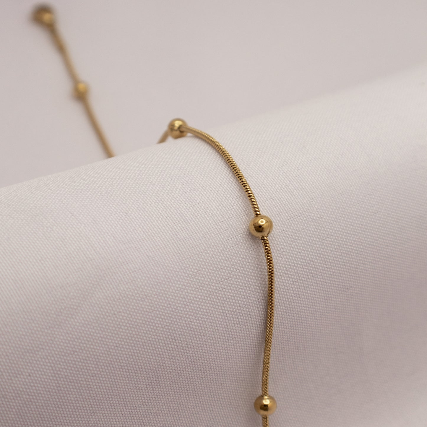 Gold bracelet on a white mannequin arm