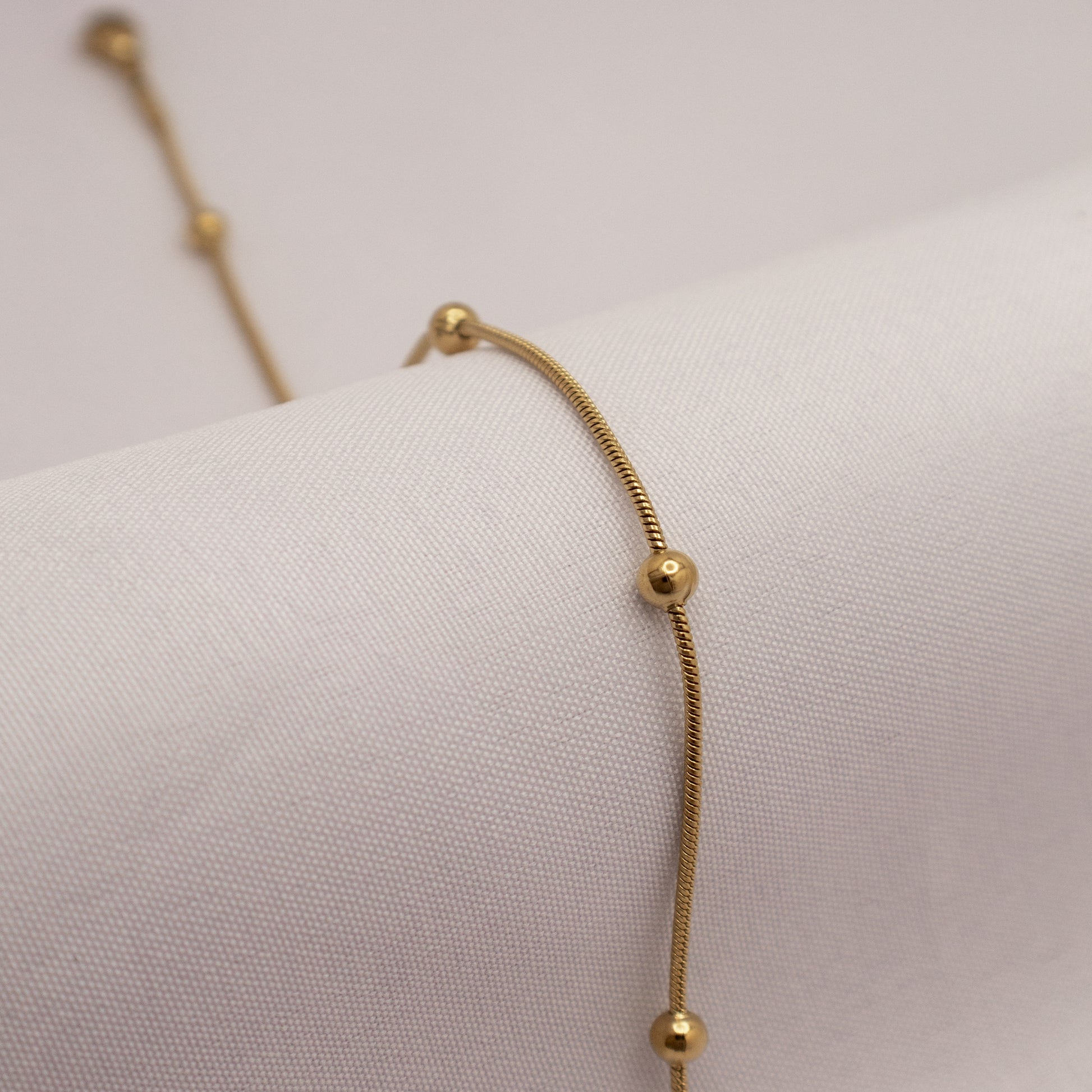 Gold bracelet on a white mannequin arm