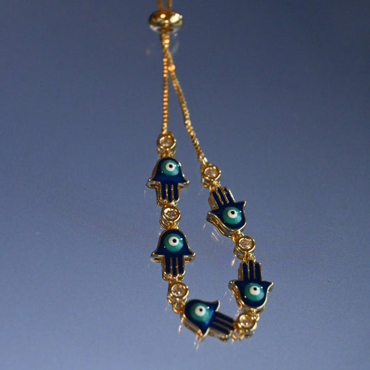 Gold and blue hamsa hand earrings on a clear background