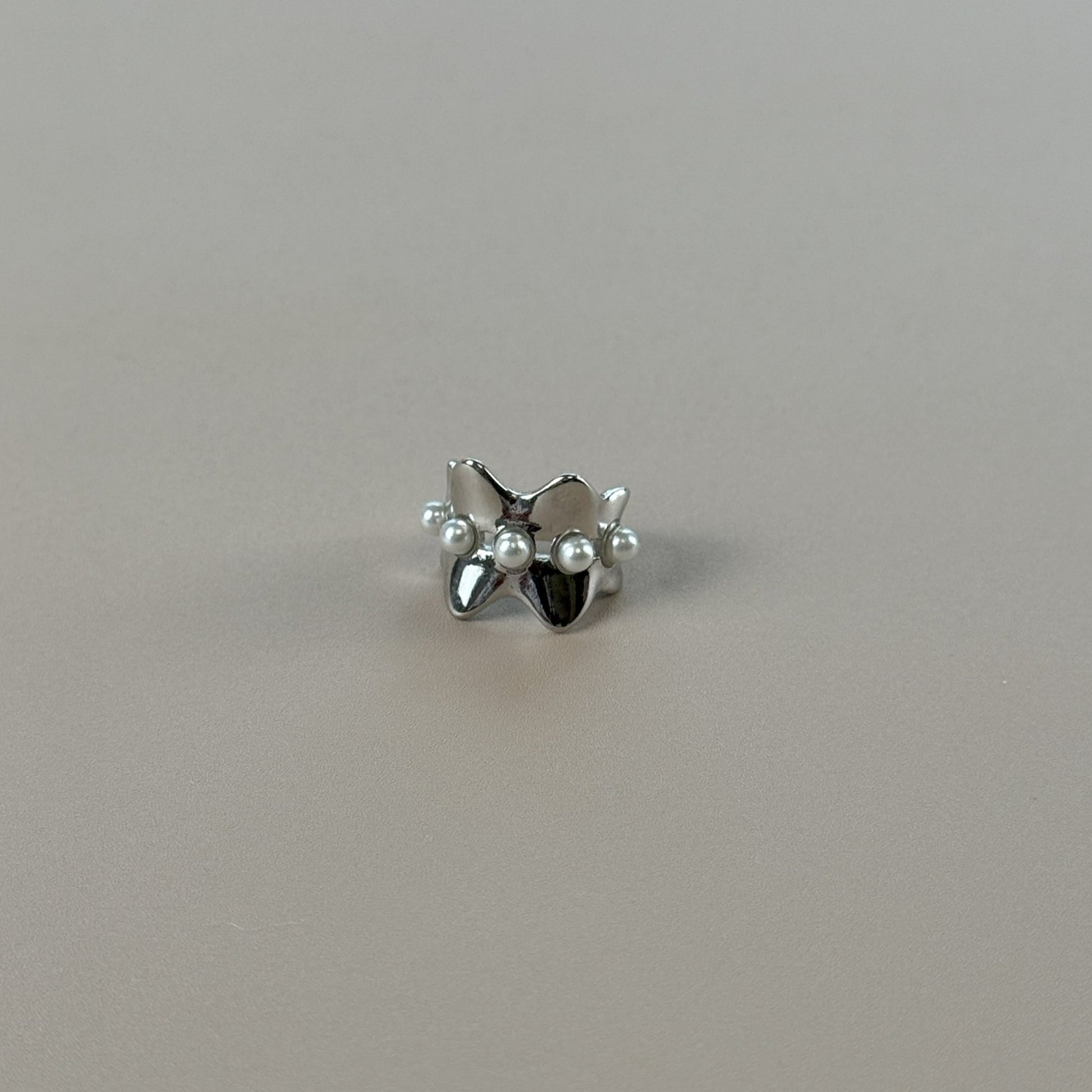 Silver earcuff with pearls on a gray background