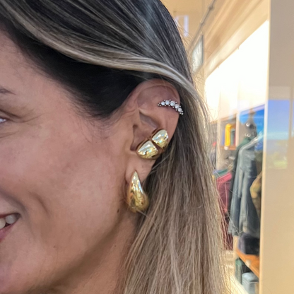 Woman wearing gold earrings in a store setting