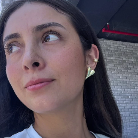 Woman wearing gold hoop earrings with a neutral background