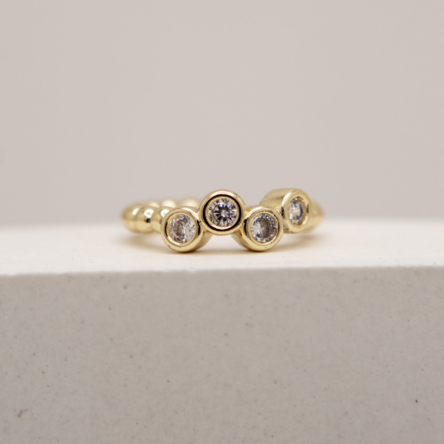 Gold ring with embedded diamonds on a light gray background