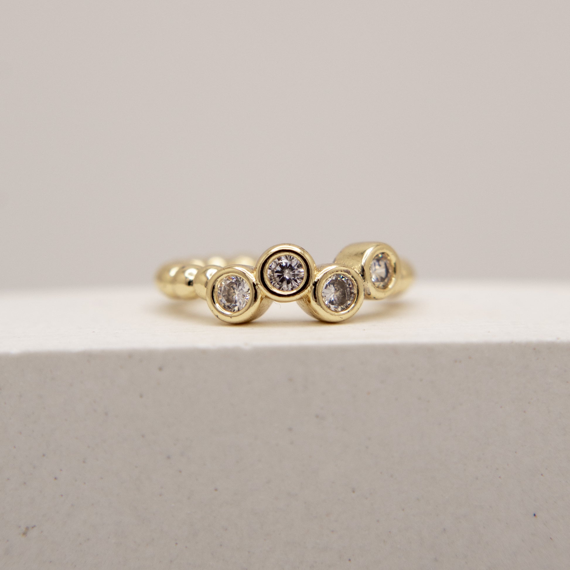 Gold ring with embedded diamonds on a light gray background