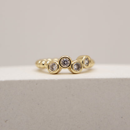 Gold ring with embedded diamonds on a light gray background
