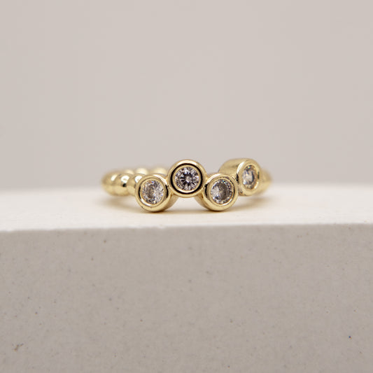 Gold ring with embedded diamonds on a light gray background