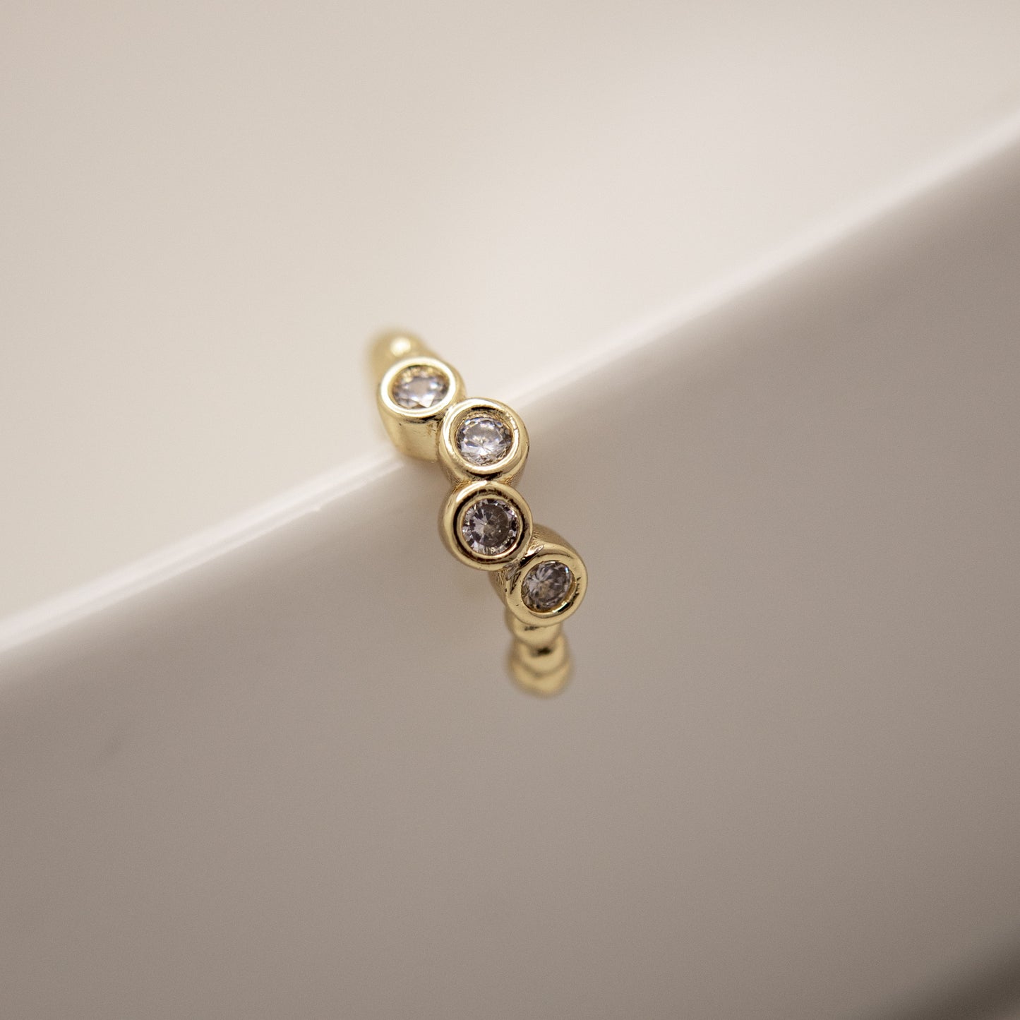 Gold earring with embedded diamonds on a beige background