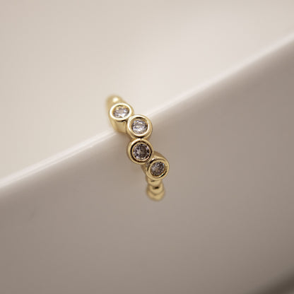 Gold earring with embedded diamonds on a beige background