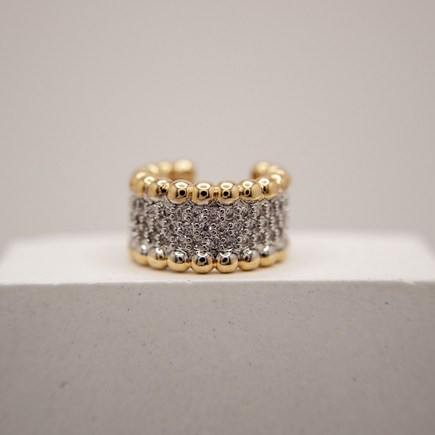 Gold and silver beaded ring on a light gray background