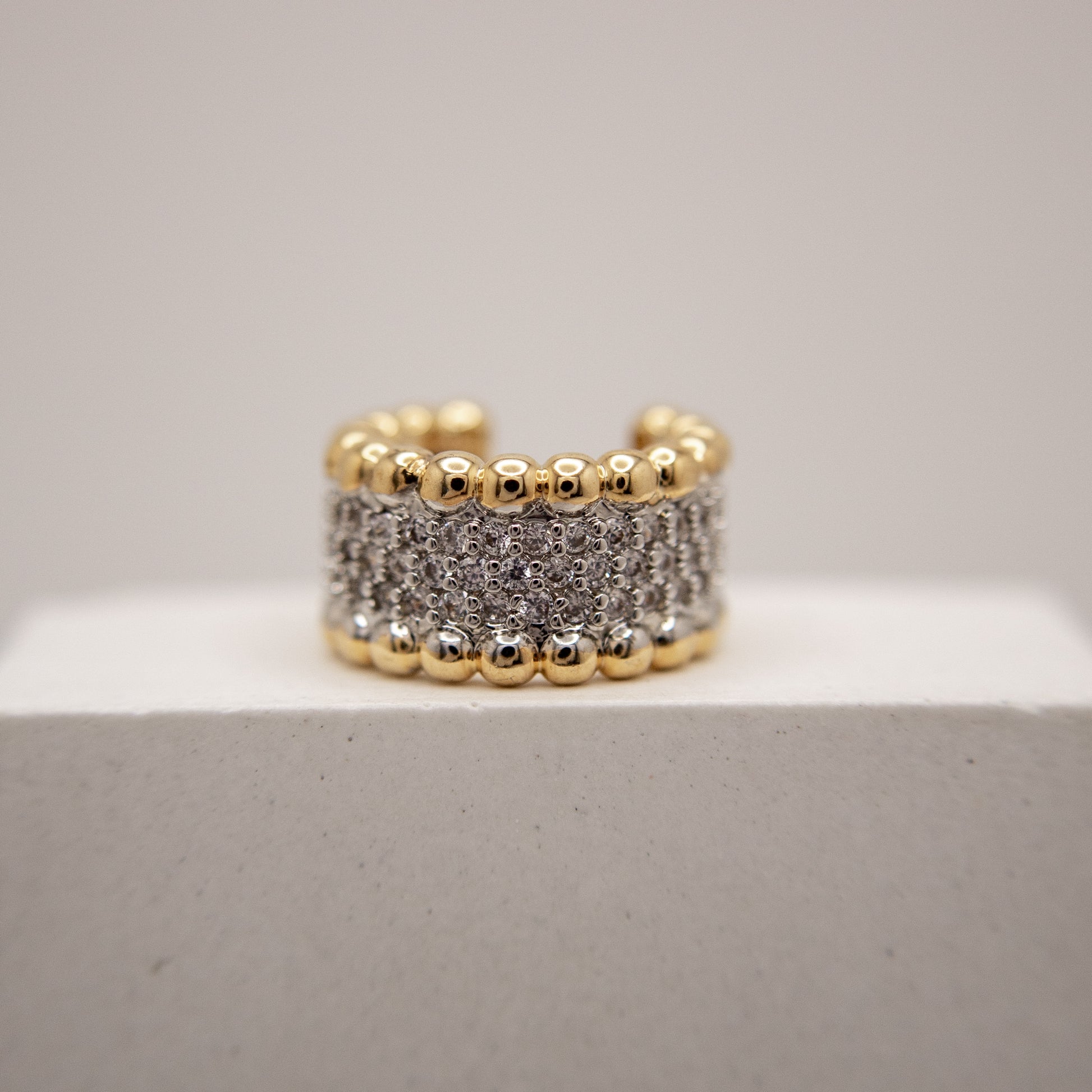 Gold and silver beaded ring on a light gray background