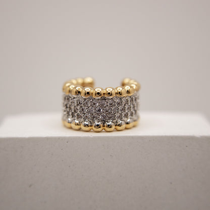 Gold and silver beaded ring on a light gray background