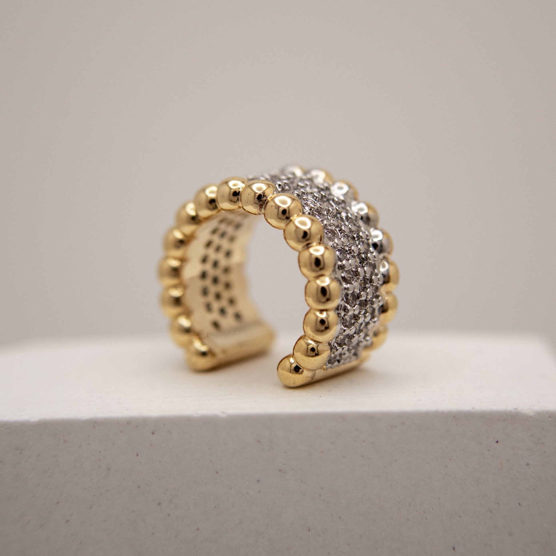 Gold and silver beaded ring on a light gray surface with a neutral background