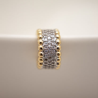 Gold and silver beaded ring on a beige background